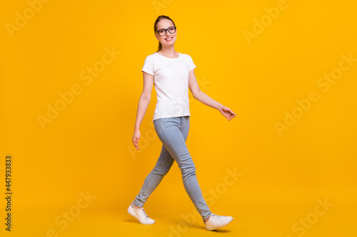 Full length photo of young woman happy positive smile go walk step isolated over yellow color background