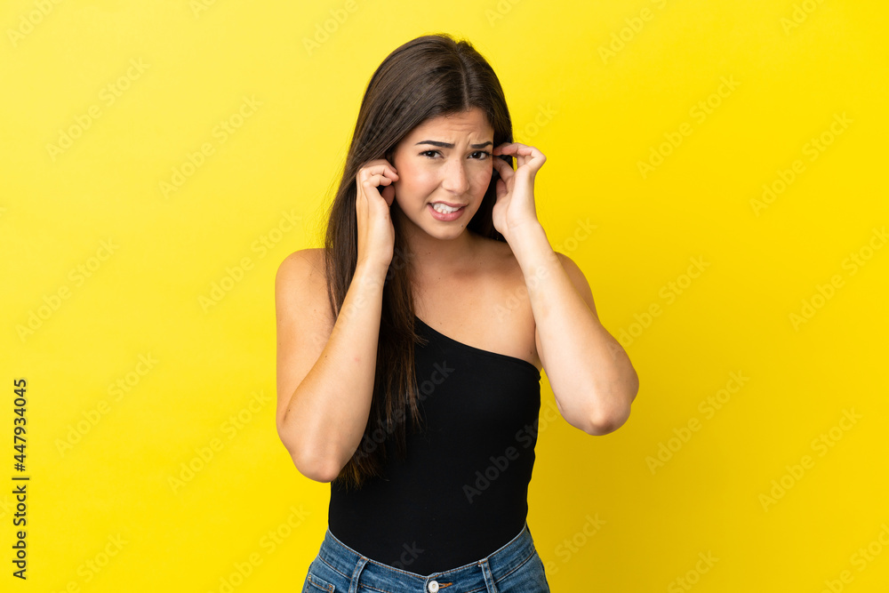 Young Brazilian woman isolated on yellow background frustrated and covering ears