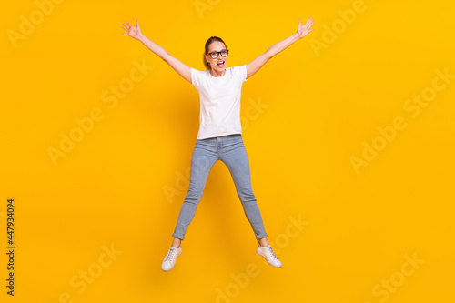 Full body photo of happy charming young woman jump up raise hands isolated on yellow color background