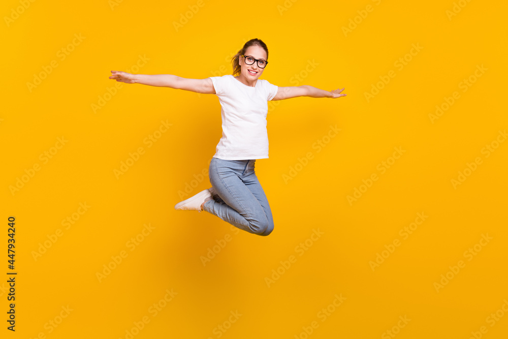 Full size profile side photo of young cheerful woman happy positive smile jump up hands wings isolated over yellow color background