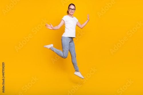 Full length photo of young woman happy positive smile jump active isolated over yellow color background © deagreez