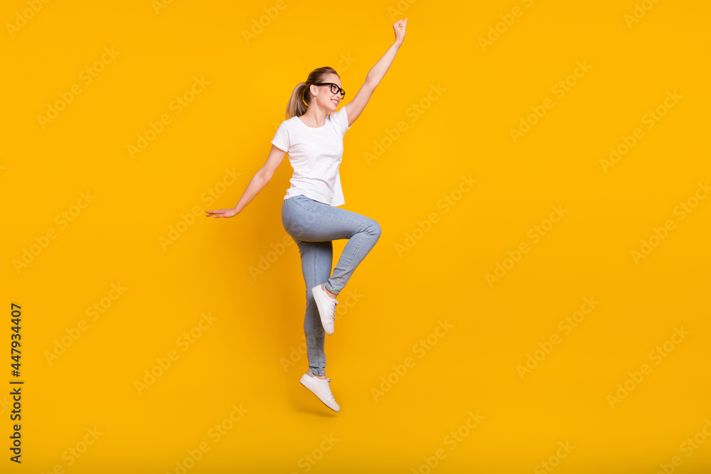 Full body profile side photo of young woman happy positive smile jump up superwoman isolated over yellow color background Full body profile side photo of young woman happy positive smile jump up superwoman isolated over yellow color background