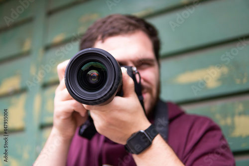 Half length of young beautiful man outdoor in the city holding digital camera, shooting - photography, creative, artist concept
