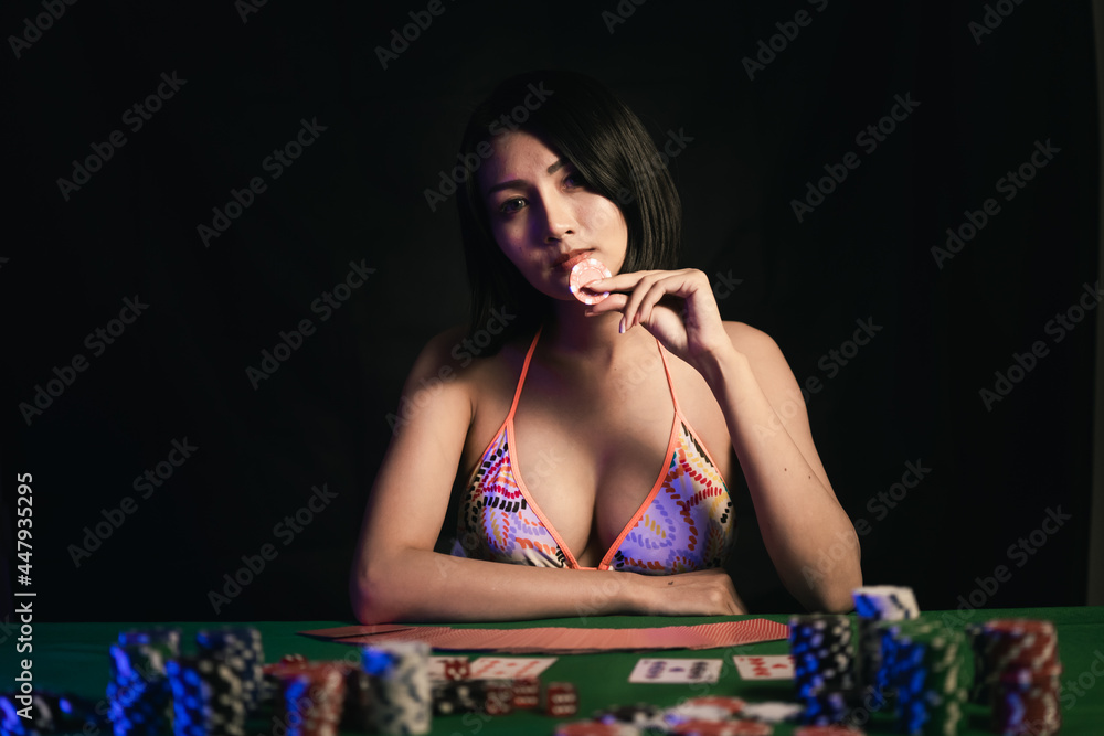 Foto Stock sexy women wearing bikini holding poker chips at the poker table  in casino | Adobe Stock