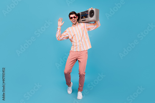 Full length photo of positive happy man dance hold hand shoulder boombox isolated on pastel blue color background