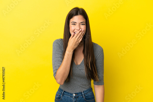 Young Brazilian woman isolated on yellow background happy and smiling covering mouth with hand