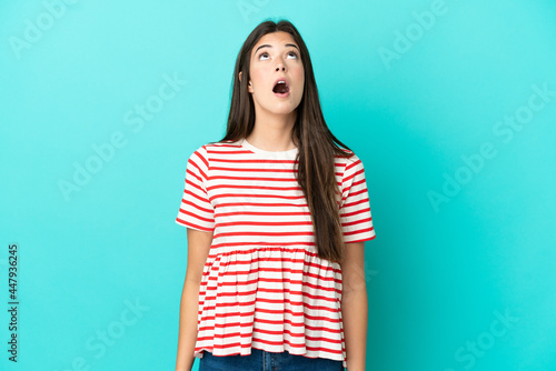 Young Brazilian woman isolated on blue background looking up and with surprised expression © luismolinero