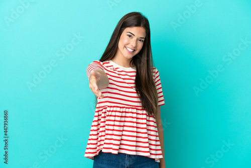 Young Brazilian woman isolated on blue background shaking hands for closing a good deal