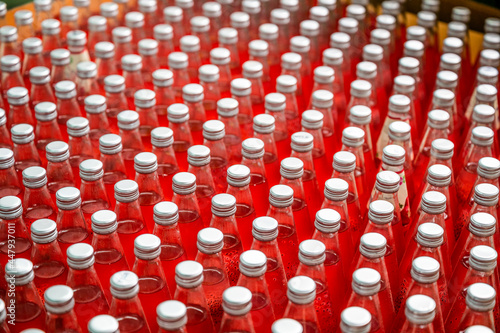 Red juice bottles with screw cap in conveyor belt at beverage processing plant