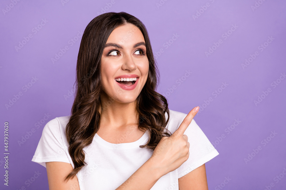 Photo of impressed brunette millennial lady look point empty space wear white t-shirt isolated on violet color background Photo of impressed brunette millennial lady look point empty space wear white t-shirt isolated on violet color background