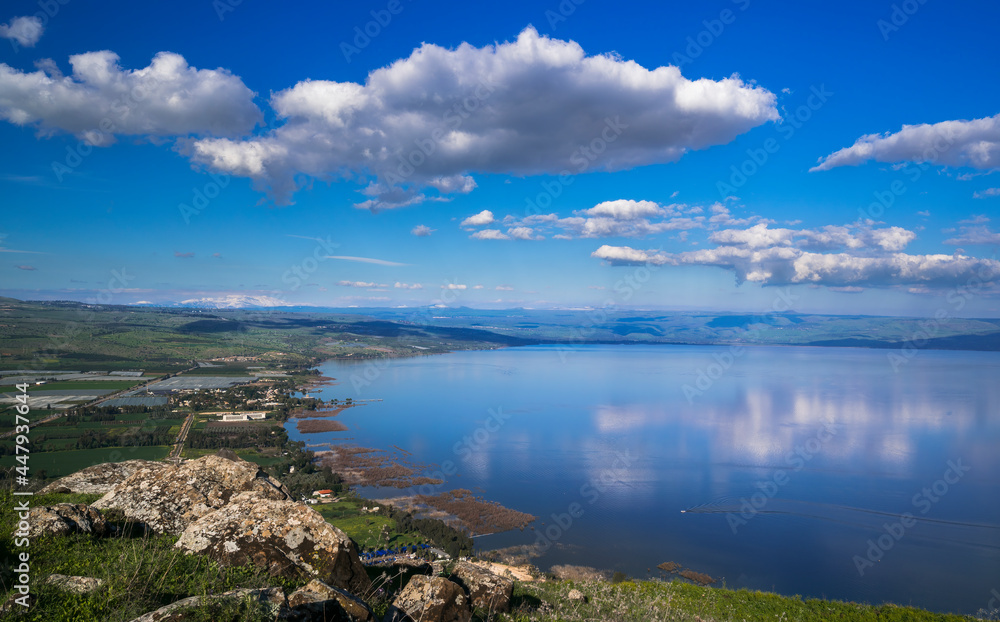 Beautiful view of the Sea of Galilee from the cliff of Mount Arbel National Park and Nature Reserve, with clouds in the sky and snow-capped Mt Hermon in the distance; Lower Galilee, Israel