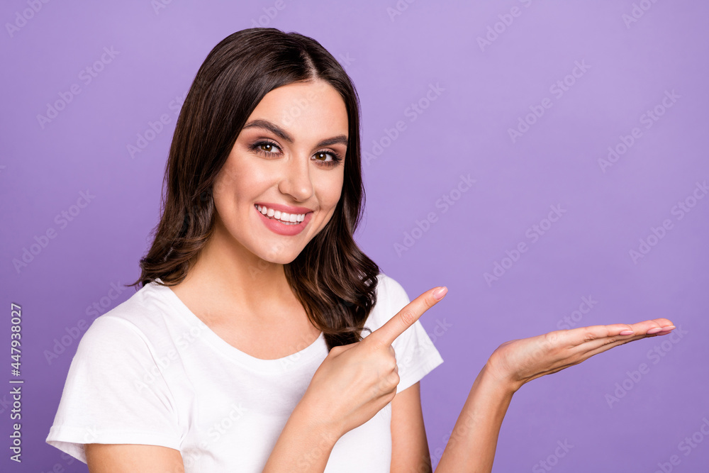 Photo of cool brunette young lady hold point empty space wear white t-shirt isolated on violet color background Photo of cool brunette young lady hold point empty space wear white t-shirt isolated on violet color background