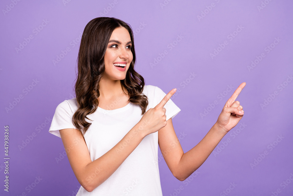 Photo of impressed brunette young lady point look empty space wear white t-shirt isolated on violet color background Photo of impressed brunette young lady point look empty space wear white t-shirt isolated on violet color background