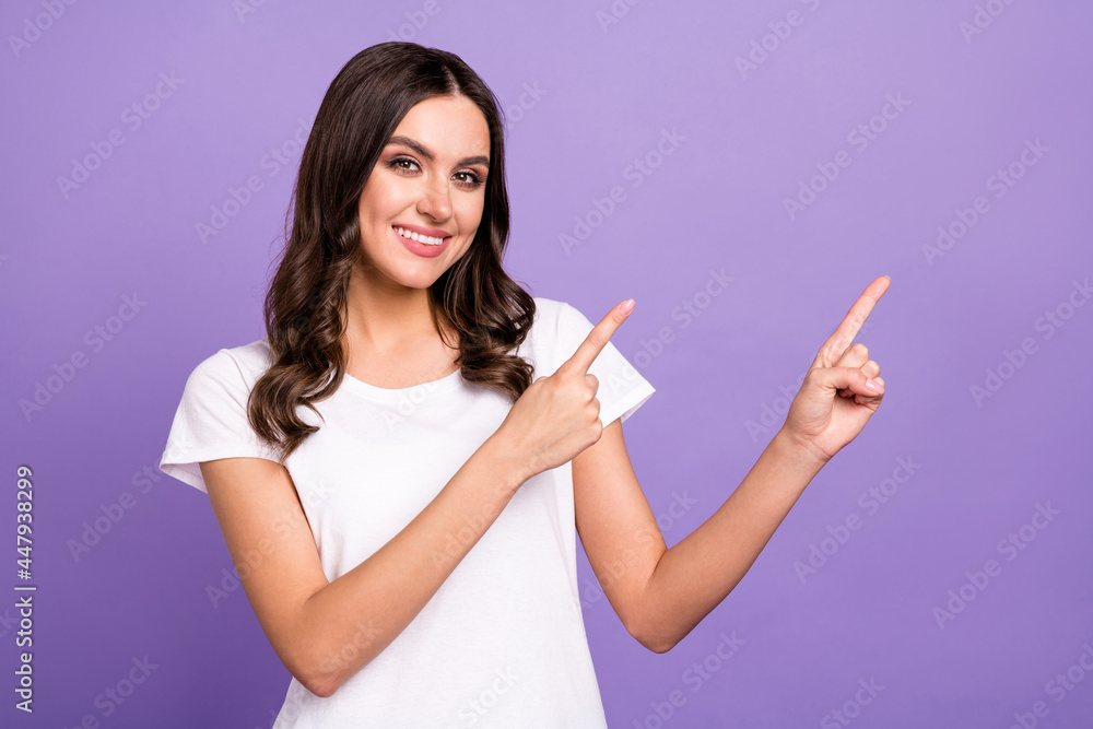 Photo of cute brunette millennial lady point empty space wear white t-shirt isolated on violet color background Photo of cute brunette millennial lady point empty space wear white t-shirt isolated on violet color background