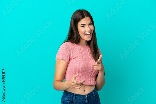 Young Brazilian woman isolated on blue background pointing to the front and smiling