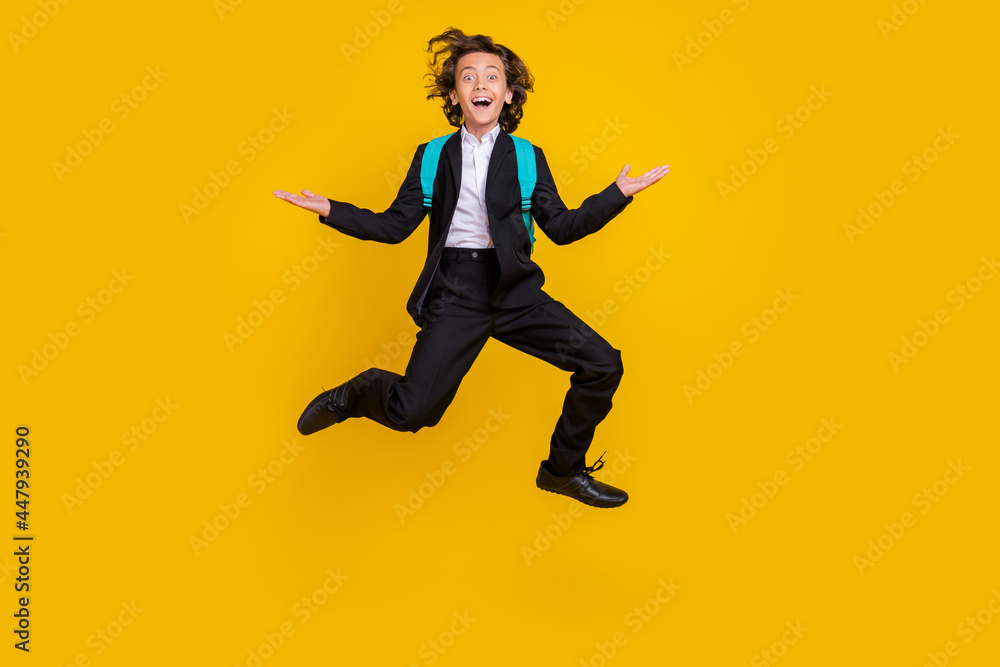 Photo of sporty energetic small boy jump excited mood wear bag black uniform isolated yellow color background