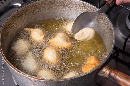 Brazilian sweet called "bolinho de Chuva", being put to fry in a pan with oil, selective focus.