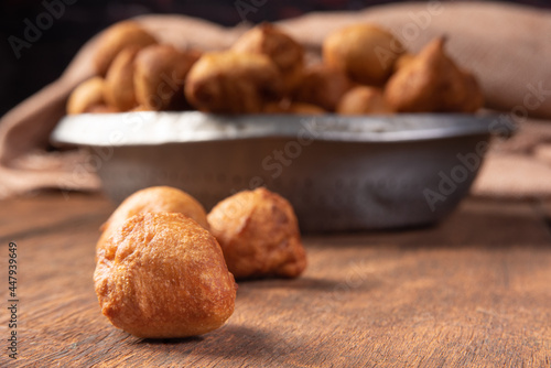 Brazilian sweet called "bolinho de Chuva", placed in an aluminum bowl on rustic wood, selective focus.