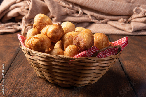 Brazilian sweet called "bolinho de Chuva", placed in a basket on rustic wood, selective focus.