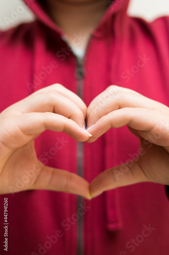Woman wearing red jacket making a heart with her hands 