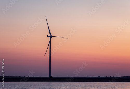 Background of the windmill on the shore at the sunset; colors of the sky are soft gradient