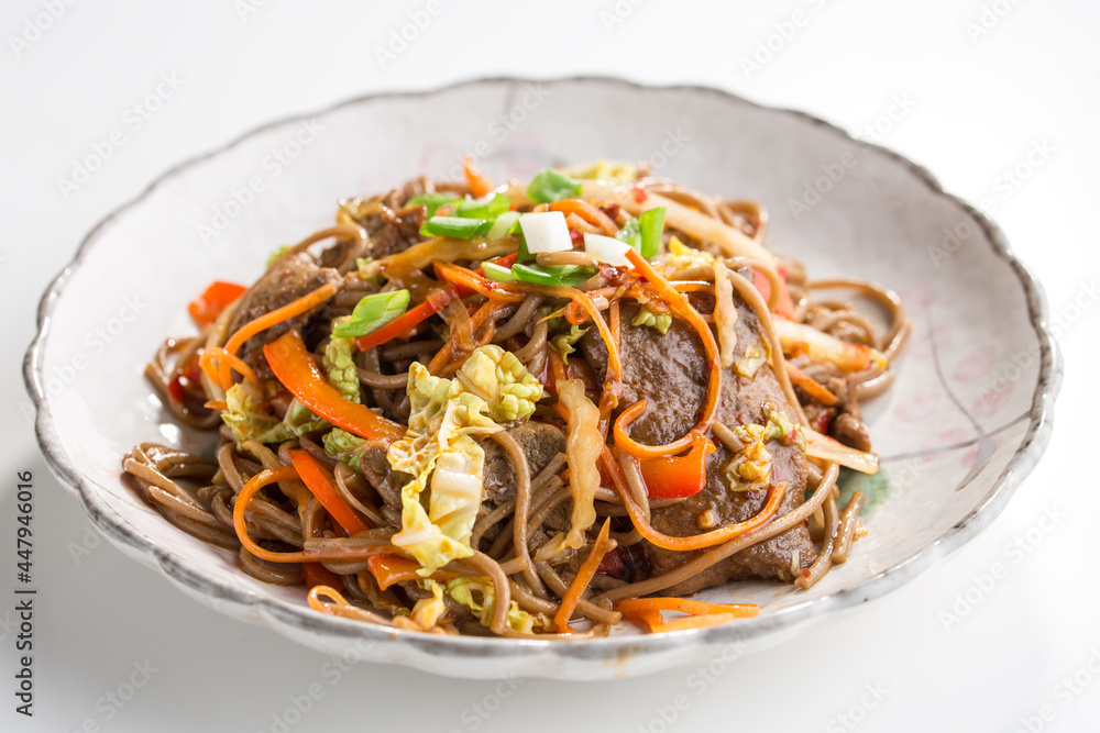 Soba noodles with beef, carrots, onions and sweet peppers isolated on white background Soba noodles with beef, carrots, onions and sweet peppers isolated on white background