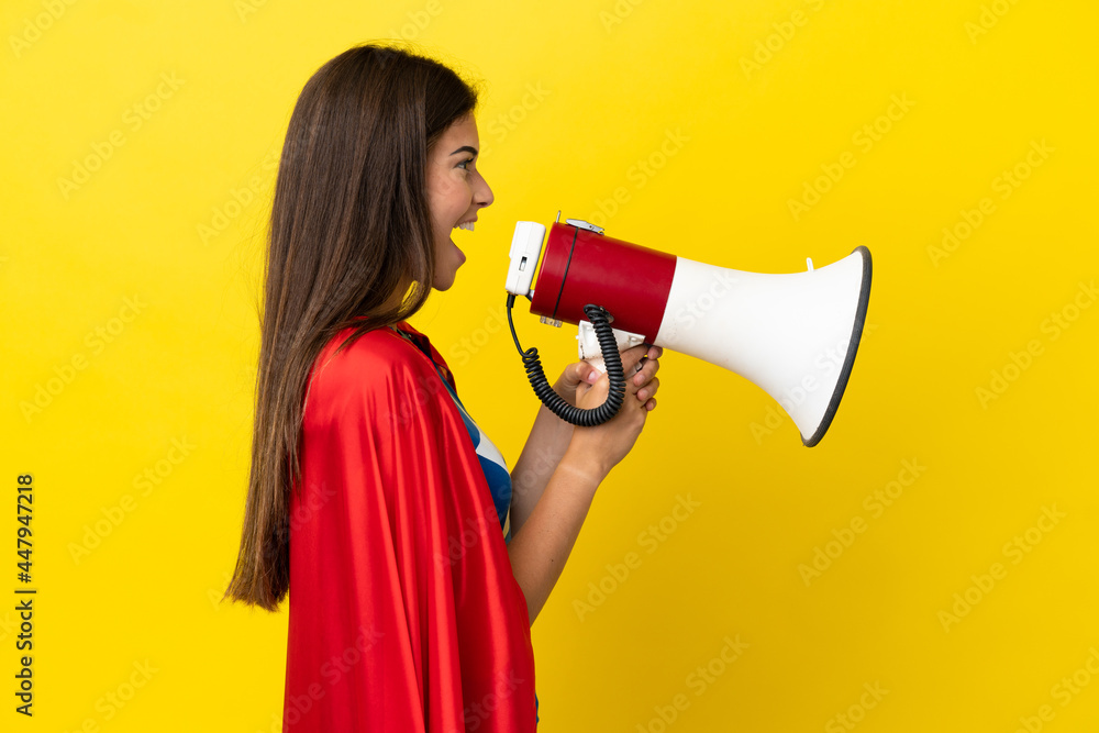 Super Hero Brazilian woman isolated on yellow background shouting through a megaphone Super Hero Brazilian woman isolated on yellow background shouting through a megaphone