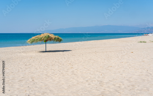 Beach umbrela on sandy beach, mediterranean sea, Calabria Italy.