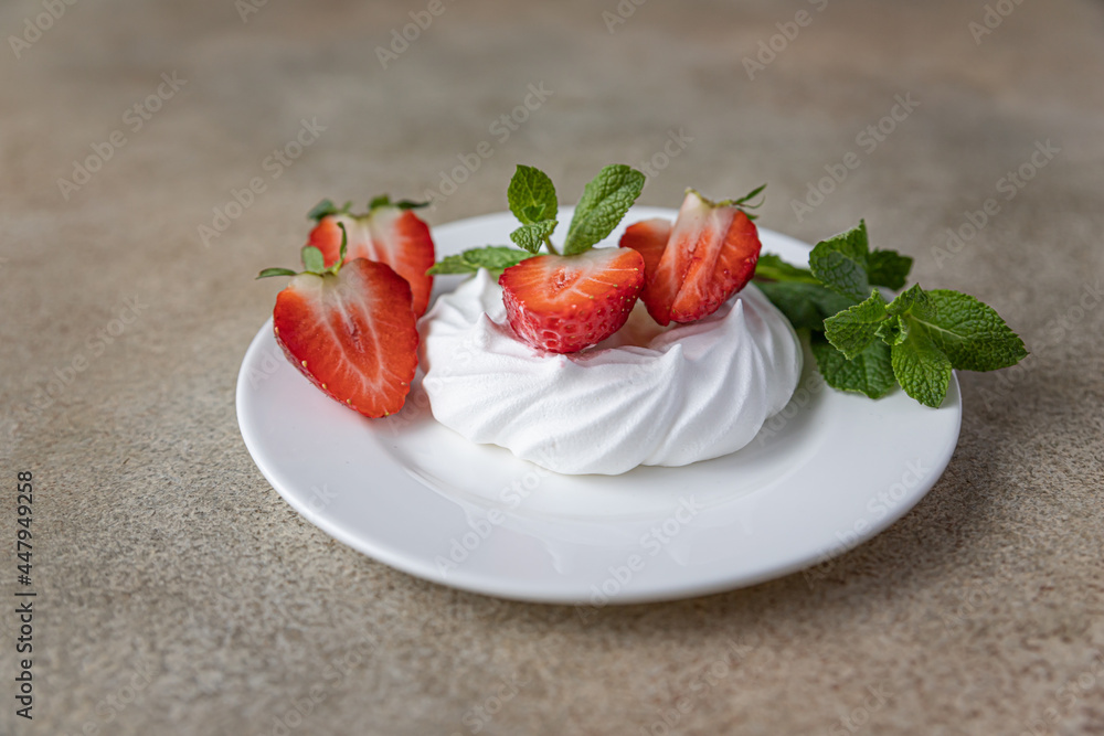 Mini Pavlova meringue cakes with strawberries and mint on a plate, concrete background. Mini Pavlova meringue cakes with strawberries and mint on a plate, concrete background.