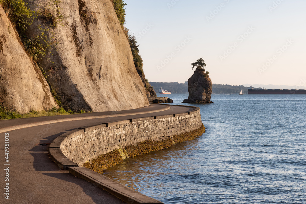 Obraz premium View of the Siwash Rock from Seawall at Stanley Park in a modern city. Downtown Vancouver, British Columbia, Canada. Sunny Summer Sunset.