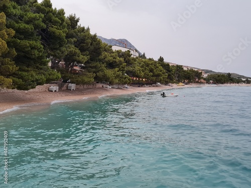 Croatian beach of Tucepi in the evening. Beautiful landscape with shoreline of Makarska Riviera and Adriatic Sea in Croatia on a cloudy summer day. Seaside view with fresh air from pine trees.