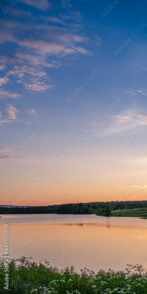 Beautiful sky sunset on a calm lake surrounded by forest in the taiga. Vertical format.