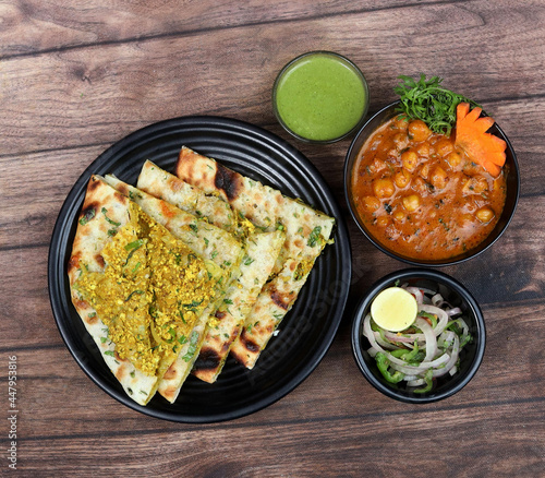 Chole Kulcha, Clay baked stuffed Naan served with channa masala or chole masala, typical meal of Amritsar, India. isolated over a rustic wooden background, selective focus