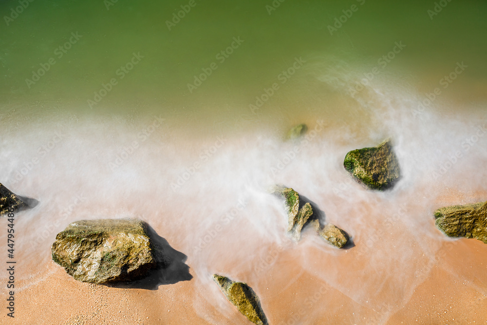 Sea sandy beach with stones, blurry water movement.