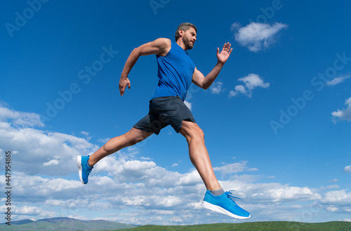 sportsman sprinter with muscular body running in sportswear outdoor on sky background, stamina.