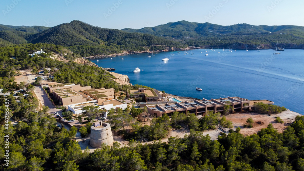 Aerial view of the round Tower (Torre) of Portinatx on the north shore of Ibiza island in Spain - Pine forests and rocky cliffs in the Balearic Islands