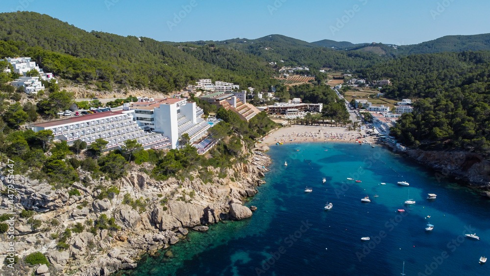 Aerial view of the beach of Port Sant Miquel on the north shore of Ibiza island in Spain - Isolated bay sided with large hillside hotels in the Balearic Islands