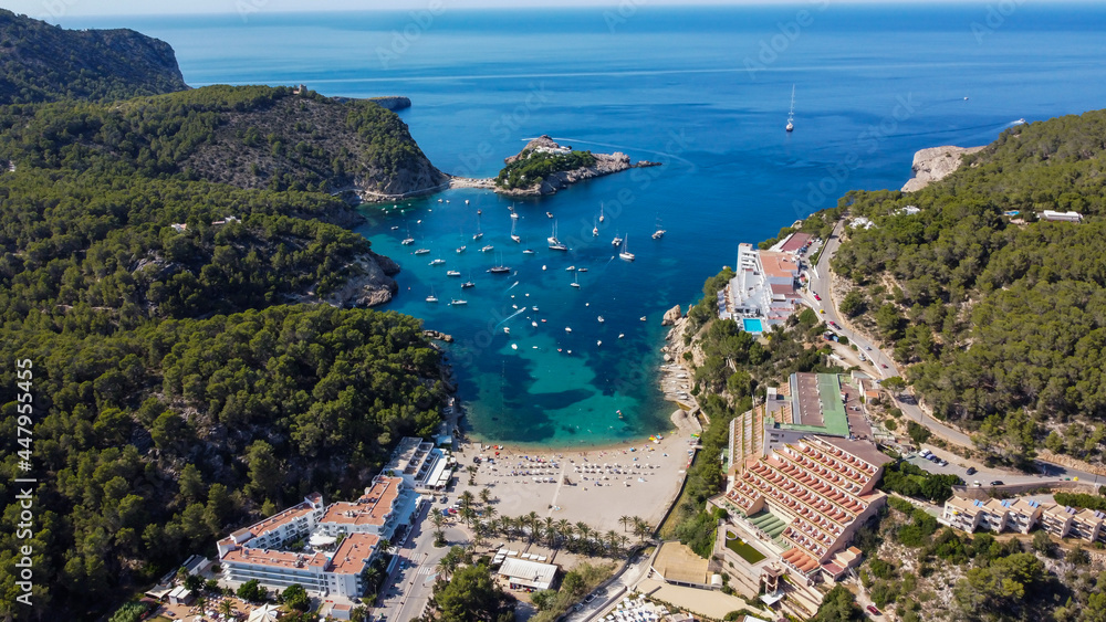 Fototapeta premium Aerial view of the beach of Port Sant Miquel on the north shore of Ibiza island in Spain - Isolated bay sided with large hillside hotels in the Balearic Islands