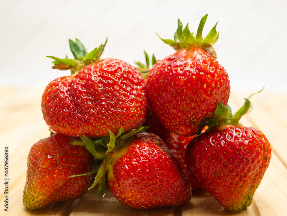 Close-up strawberries with leaves. Ripe red berries lie in a heap on the table. Delicious aromatic berries. Close-up strawberries with leaves. Ripe red berries lie in a heap on the table. Delicious aromatic berries.