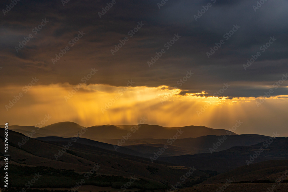 Obraz premium Sunlight filters through the clouds as the sun sets