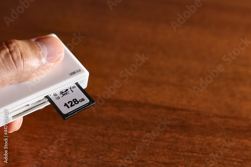 The man inserts a 128GB SD card into the card reader. Media for transmission and storage of information. Information Technology. photo