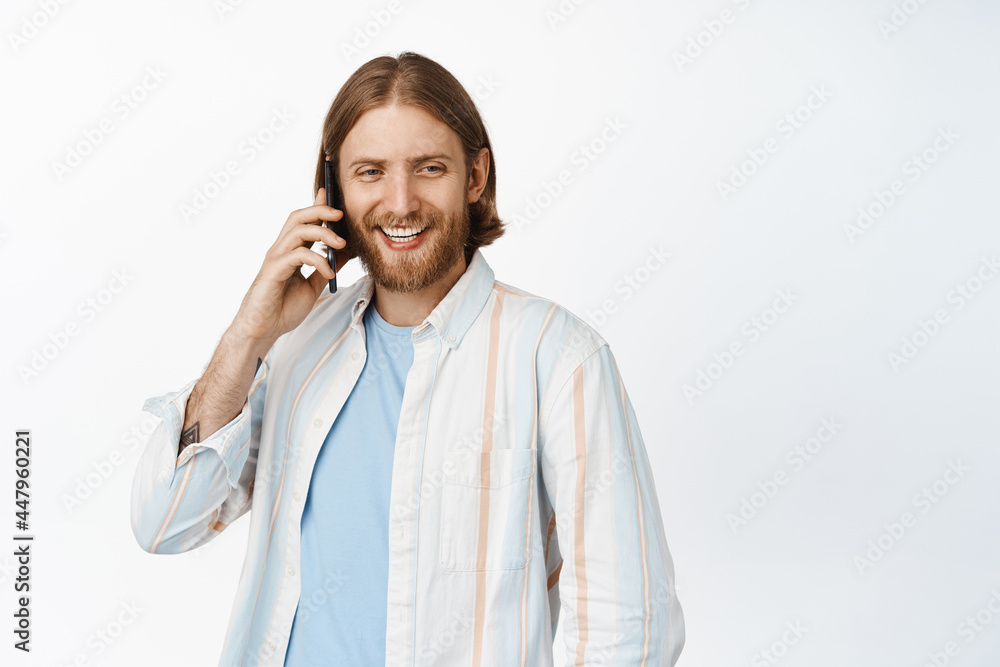 Image of handsome bearded man talking on mobile phone and smiling, casually laughing during cellphone call, cellular advertisement, white background Image of handsome bearded man talking on mobile phone and smiling, casually laughing during cellphone call, cellular advertisement, white background