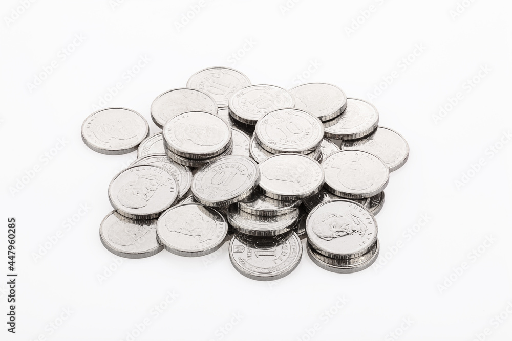 Close-up of a heap of 10 hryvnia coins, on a white background. Ukrainian coins
