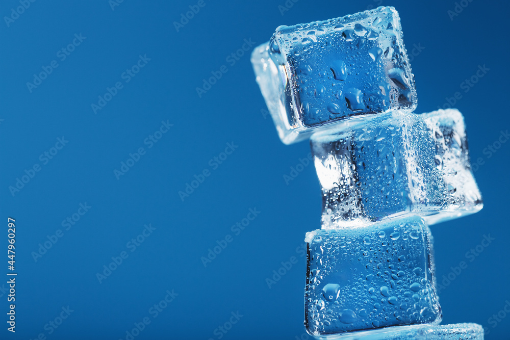 Ice cubes with water drops tower in a row on a blue background. Ice cubes with water drops tower in a row on a blue background.