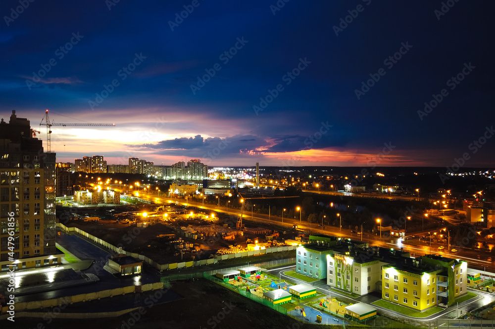 Fototapeta premium Top view of the lights of the night city. Setting sun, twilight. Traces of lights from moving cars