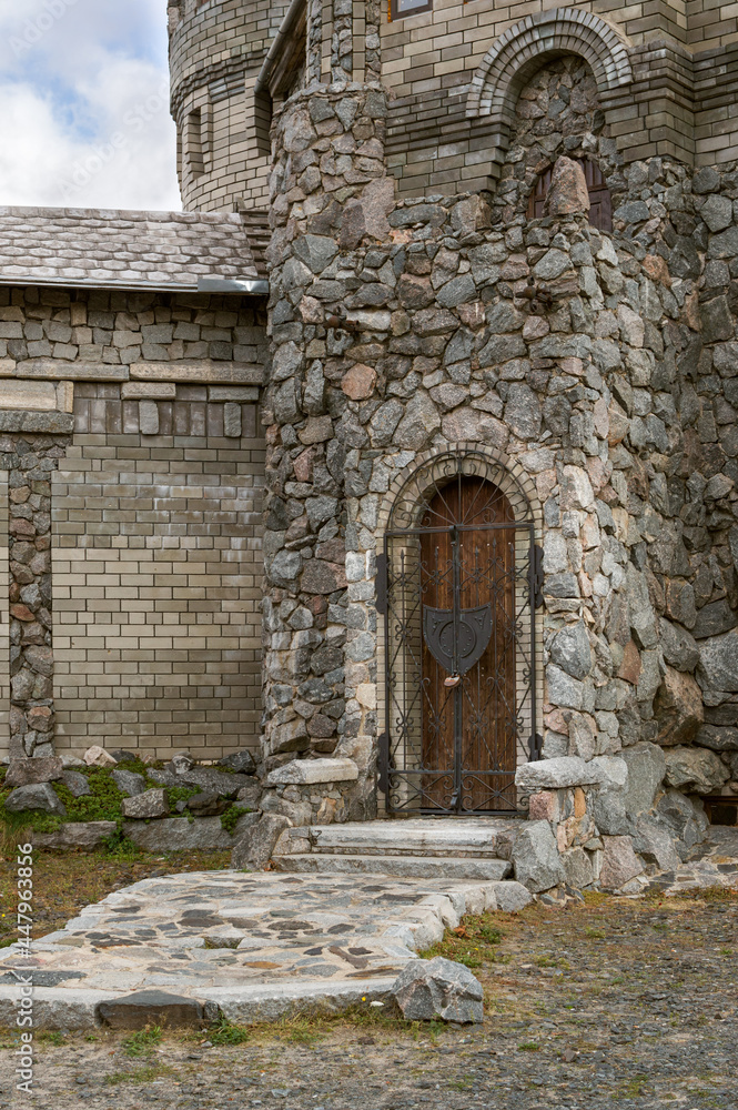 Fototapeta premium Wall of stone castle, door with wrought-iron lattice