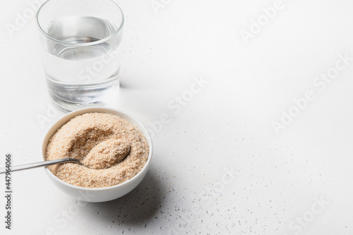 Psyllium husk and glass of water soluble fiber supplement for intestinal on a white background. Superfood for healthy, lowers cholesterol, balances blood sugar, boosts weight loss. Copy space. photo