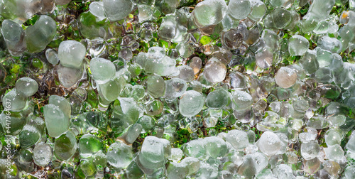 Fundo e textura abstrata de cristais naturais de gelo sobre a grama verde.