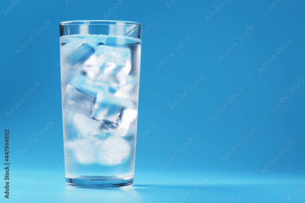 Glass with water and ice cubes on a blue background Glass with water and ice cubes on a blue background