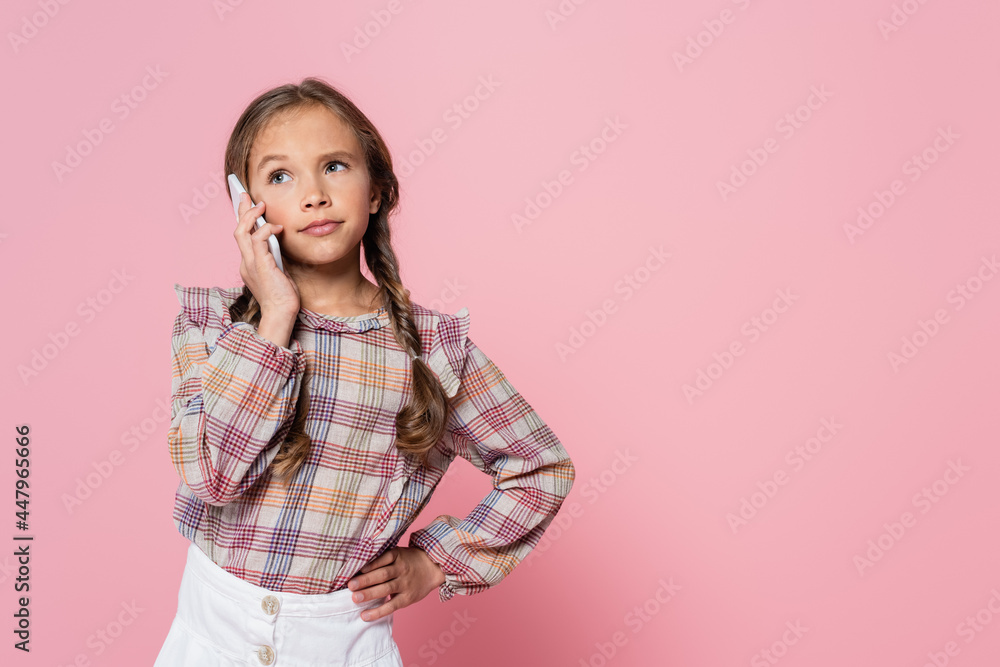 serious preteen girl talking on smartphone while standing with hand on hip isolated on pink serious preteen girl talking on smartphone while standing with hand on hip isolated on pink